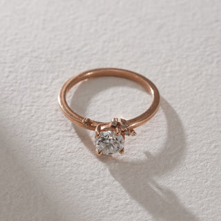 op flat lay view of Whimsical Floral Diamond Engagement Ring in rose gold with a central solitaire and clustered floral diamonds, casting a soft shadow on the beige textured background.