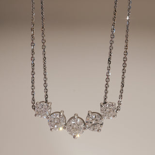 Front view of Five-Stone Sparkler Diamond Necklace against beige background. Designed in 14KT hallmarked white gold, size 14, adorned with EF colour, VVS clarity lab grown diamonds totaling 2.54 carats, including a solitaire of 0.62 carats. Product weighs 5.57 grams, elegant and radiant.