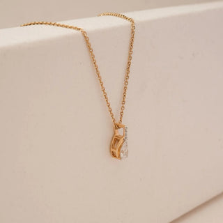 Side view of pear-shaped lab grown diamond pendant set in a sculpted yellow gold swirl frame with pavé diamond detailing, suspended from a delicate gold chain on a neutral backdrop.