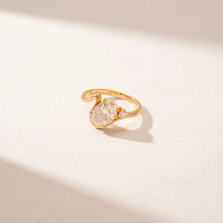 Side view of a 14KT Yellow Gold diamond ring featuring a large oval centre diamond, a curved crossover band and a round diamond accent.