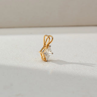 Side view of a yellow gold pendant featuring a princess-cut solitaire diamond in a four-prong basket setting, highlighted on a neutral surface with a polished double-loop bail.