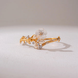 Front view of the Elegant Floral Pearl Gold Bracelet in 14KT yellow gold, featuring floral motifs with diamonds and pearl-inspired detailing. Captured against a soft beige backdrop, the design reflects timeless elegance.
