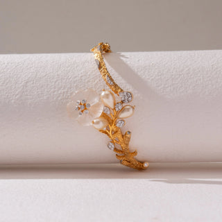 Side view of the Elegant Floral Pearl Gold Bracelet in 14KT yellow gold, featuring floral motifs with diamonds and pearl-inspired detailing. Captured against a soft beige backdrop, the design reflects timeless elegance.
