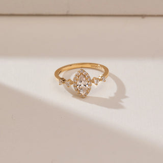 Angled top view of 14KT yellow gold ring with a marquise-cut centre diamond, surrounded by a halo of round diamonds and accented with pear-shaped side stones.