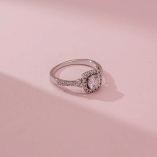 Top view of Reia’s 14 KT White Gold Eternal Grace Halo Solitaire Diamond Ring, showing a round stone and halo. Set against pink, it highlights high-shine, symmetrical elegance.