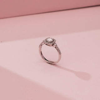 Side view of Reia’s 14 KT White Gold Eternal Grace Halo Solitaire Diamond Ring, showing a round centre stone and diamond halo. Set against pink, it highlights a luminous, symmetrical design.