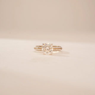 Close-up view of a 14KT Yellow Gold diamond ring with a round centre stone and pavé-set double band.