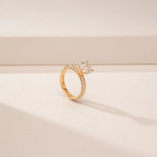 Angled view of a 14KT Yellow Gold diamond ring with a round centre stone and pavé-set double band.