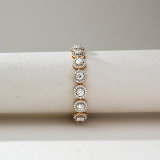 Front view of Round Halo Diamond Bracelet in 14KT Dual Gold, featuring round lab grown diamonds encircled by halo settings in a continuous design. Set on a beige backdrop, the design highlights symmetry and brilliance.

