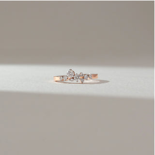 Front view of floral cluster diamond ring in rose gold, featuring pear-shaped and round lab-grown diamonds arranged in a delicate cluster across a slim band. Set on a soft neutral backdrop, it reflects subtle elegance.