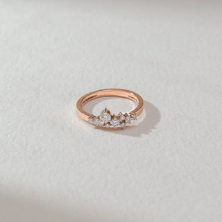 Top view of floral cluster diamond ring in rose gold, featuring pear-shaped and round lab-grown diamonds arranged in a delicate cluster across a slim band. Set on a soft neutral surface, it reflects graceful sparkle.