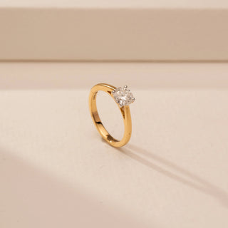 Angled view of a 14KT Yellow Gold diamond ring, featuring a round centre diamond in a four-prong setting.