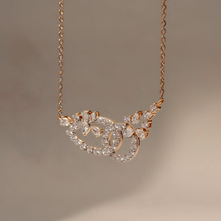 Close Up view of a diamond pendant necklace in 14 KT Rose Gold, featuring an abstract floral-inspired pavé diamond motif suspended from a delicate chain against a soft neutral backdrop.
