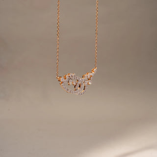 Side view of a diamond pendant necklace in 14 KT Rose Gold, featuring an abstract floral-inspired pavé diamond motif suspended from a delicate chain against a soft neutral backdrop.
