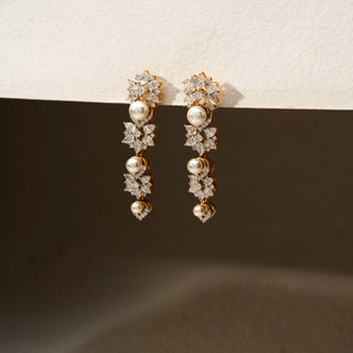 Side view of diamond and pearl drop earrings in 14 KT Yellow Gold, featuring floral diamond clusters, lustrous pearl accents, and cascading motifs against a neutral backdrop.
