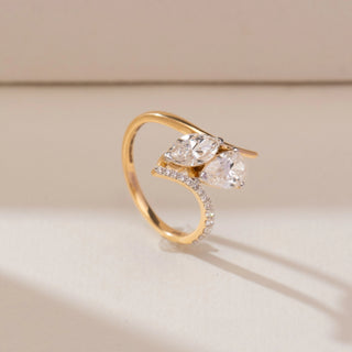 Side angle view of 14KT yellow gold bypass ring featuring pear and marquise-shaped diamonds with delicate pavé-set accents along the curved band.