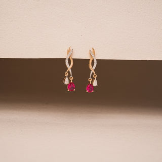Front view of Réia’s Linear Spiral Diamond Drop Earrings on a pink background, showcasing the elegant bar silhouette wrapped in tri-tone gold spirals with round-cut lab-grown diamonds. A graceful blend of minimalism and movement, ideal for everyday sophistication.
