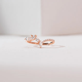 Front view of a 14KT rose gold marquise chevron diamond ring with marquise-cut diamonds forming a V-shaped cluster and a delicate pavé-set band, displayed on a soft neutral background.