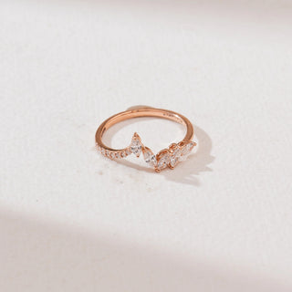 Top angle view of a 14KT rose gold marquise chevron diamond ring with marquise-cut diamonds forming a V-shaped cluster and a delicate pavé-set band on a soft neutral surface.