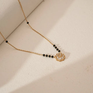 Top view of yellow gold floral diamond mangalsutra featuring round lab grown diamonds set in a petal motif with traditional black bead chain, displayed on a soft neutral background.