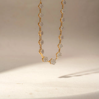Side view of a floral diamond station necklace in 14 KT Yellow Gold, featuring flower-shaped lab-grown diamond clusters in raised settings along a delicate chain, against a beige backdrop.