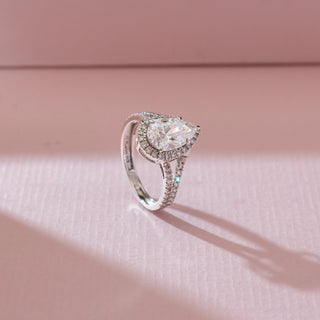 Side angled view of pear-shaped halo diamond ring in white gold, featuring a central lab-grown diamond with pavé-set halo and split band. Captured against a soft pink background.
