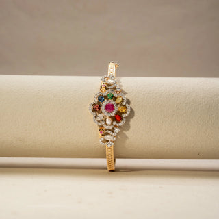Front view of a multicolour gemstone and diamond bracelet in 14 KT Yellow Gold, featuring a floral cluster of vibrant gemstones framed by pavé-set diamonds, displayed against a soft beige backdrop.
