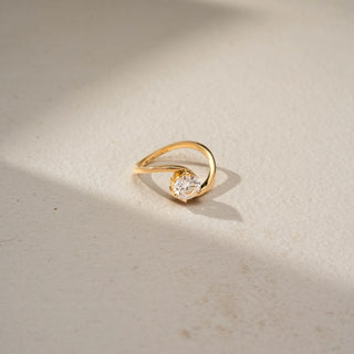 Side view of a marquise solitaire engagement ring in 14 KT Yellow Gold, featuring a marquise-cut lab-grown diamond embraced by a split pavé diamond band, displayed against a beige backdrop.