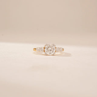 Front view of a 14KT Yellow Gold diamond ring, featuring a round centre diamond and diamond-set side stones.