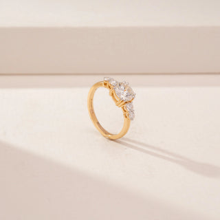 Angled view of a 14KT Yellow Gold diamond ring, featuring a round centre diamond and diamond-set side stones.
