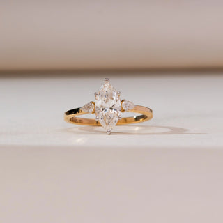 Front view of Marquise Pear Trio Diamond Ring in yellow gold, featuring a marquise-cut lab-grown diamond flanked by pear-shaped diamond accents, displayed on a soft beige backdrop.