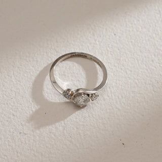 Top view of Asymmetrical Three-Stone Diamond Engagement Ring on beige background. Crafted in 14KT hallmarked white gold, size 12, featuring EF VVS lab grown diamonds weighing 0.65 carats in total, with a 0.51-carat solitaire. Ring weighs 2.15 grams, priced INR 15,000–50,000.