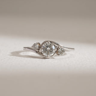 Front view of Asymmetrical Three-Stone Diamond Engagement Ring against beige background. 14KT hallmarked white gold, size 12, set with EF colour, VVS clarity lab grown diamonds totaling 0.65 carats, including a 0.51-carat solitaire. Weight 2.15 grams, priced INR 15,000–50,000.