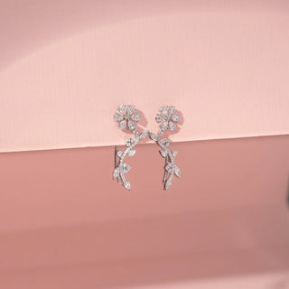 Close up view of Floral Vine Drop Diamond Earrings in 14KT White Gold, featuring flower motifs and leaf-shaped diamonds.
