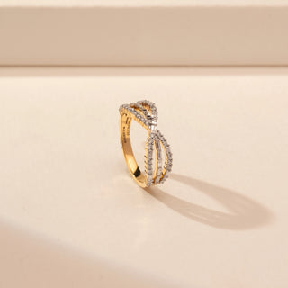 Angled view of a 14KT Yellow Gold diamond ring with an infinity-inspired crossover design and diamond-set bands.