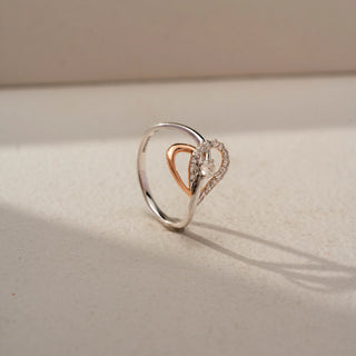 Angled front view of a dual-tone heart-shaped lab-grown diamond ring in 14 KT white and rose gold, featuring an open heart design with a sparkling diamond halo and centre stone.