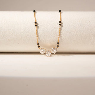 Close-up view of 14KT Yellow Gold diamond mangalsutra 
 featuring three round diamonds and black bead accents along the chain.