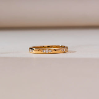 Front view of Celestial Starburst Gold Diamond Band in 14KT yellow gold, showcasing round diamonds set in a subtle starburst pattern across a sleek polished band.