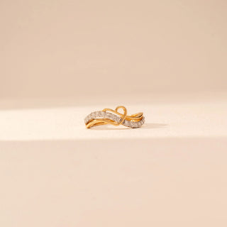 Front view of a 14KT yellow gold ring featuring round-cut diamonds in a crossover design, set against a beige background.
