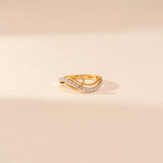 Close-up view of a 14KT yellow gold ring featuring round-cut diamonds in a crossover design, set against a beige background.