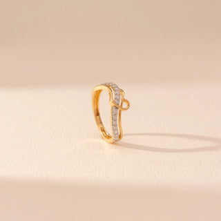 Angled view of a 14KT yellow gold ring featuring round-cut diamonds in a crossover design, set against a beige background.