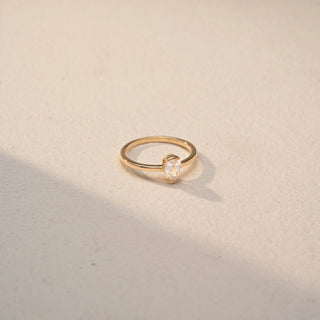 Side view of a pear solitaire ring in 14 KT Yellow Gold, featuring a pear-shaped lab-grown diamond in a classic three-prong setting, displayed against a beige backdrop.
