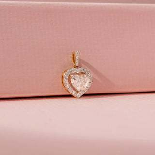 Side view of a 14KT white gold pendant featuring heart and round-cut diamonds, set against a pink background.