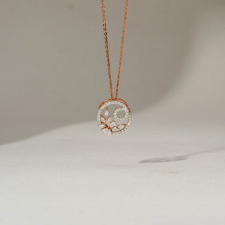 Front view of a rose gold pendant necklace featuring a circular diamond-studded floral design, suspended from a delicate chain against a soft neutral background.