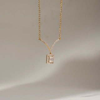 Angled view of an emerald-cut lab-grown diamond halo pendant in 14 KT yellow gold, featuring a rectangular pavé-set halo, diamond-accented V-shaped bail, and a delicate matching chain.