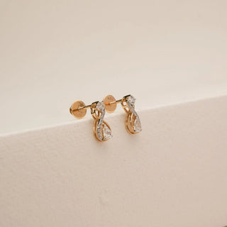 Side view of infinity loop diamond earrings featuring round and pear-shaped lab-grown diamonds set in yellow gold, highlighting the curved silhouette and layered diamond detailing.