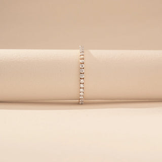 Front view of a 14KT dual gold bracelet featuring round-cut diamonds in a contour design, set against a beige background.