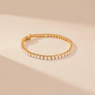 Top view of a 14KT dual gold bracelet featuring round-cut diamonds in a contour design, set against a beige background.