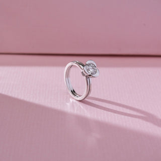 Side angled view of solitaire diamond ring in white gold, featuring a round lab-grown diamond in a smooth bezel-style setting. Captured against a soft pink background with gentle shadows.