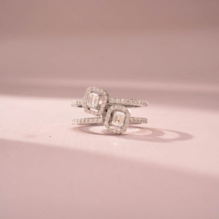 Front view of a double halo wrap ring in White Gold, featuring two emerald-cut lab-grown diamonds framed by sparkling halo settings on an open-ended pavé-set band, displayed against a soft pink backdrop.
